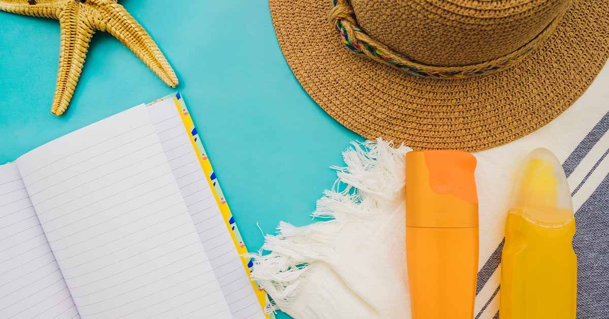 Swimming towel covered with a beach hat, starfish, sunscreen, and a journal.